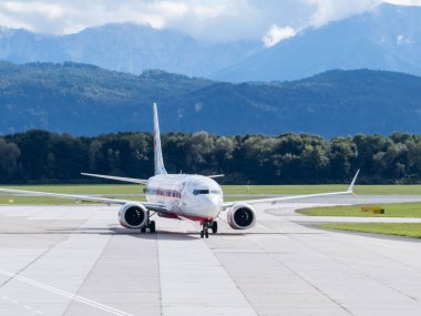 Klagenfurt, Avusturya - 25 Eylül 2025: Havaalanında, yemyeşil ve görkemli dağlarla çevrili uçaklar bir seyahat ortamı yaratıyor.