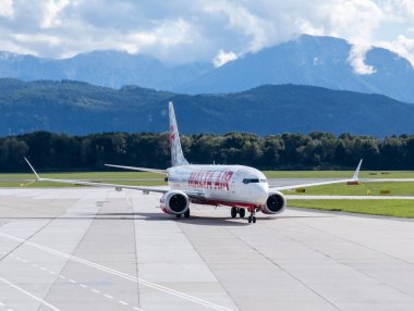 Klagenfurt, Avusturya - 25 Eylül 2025: Virgin Atlantic uçağı arka planda çarpıcı dağ manzarasıyla havaalanının pistinde taksicilik yapıyor