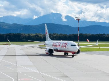 Klagenfurt, Avusturya - 25 Eylül 2025: Malta Hava Yolları, arka planda çarpıcı dağ manzarası, seyahat ve havacılık ile pistte taksicilik yapıyor