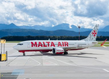 Klagenfurt, Avusturya - 25 Eylül 2025: Malta Air Boeing 737 uçakları arka planda çarpıcı dağ manzarasıyla pistte konuşlandırıldı