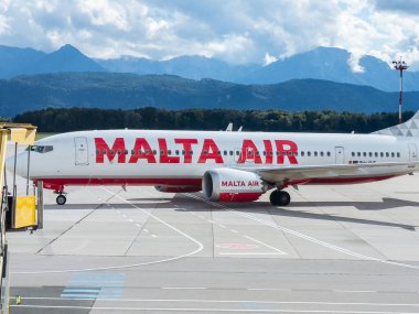 Klagenfurt, Avusturya - 25 Eylül 2025: Malta Havaalanı 'nda arka planda dağlar bulunan uçaklar çarpıcı tasarım ve havacılık özelliklerini vurguluyor