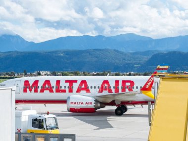 Klagenfurt, Avusturya - 25 Eylül 2025: Malta Hava Yolları uçakları çarpıcı dağ manzarası ve parlak gökyüzü ile havalimanında konuşlandırıldı.