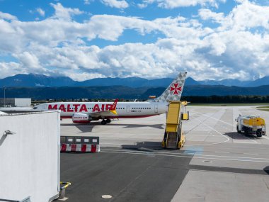 Klagenfurt, Avusturya - 25 Eylül 2025: Malta Hava Yolları uçakları çarpıcı dağ manzaralı havaalanı kapısında konuşlandırıldı.