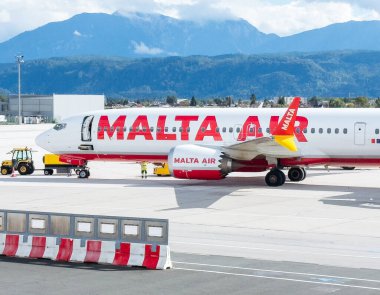 Klagenfurt, Avusturya - 25 Eylül 2025: Malta Hava Yolları, arkasında çarpıcı dağlar bulunan havaalanında konuşlandırıldı.