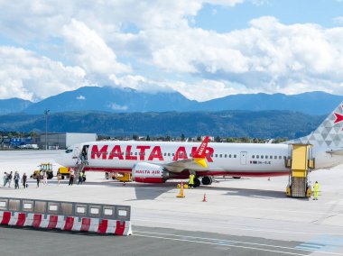 Klagenfurt, Avusturya - 25 Eylül 2025: Malta Hava Yolları havaalanından ayrılan ve arka planda çarpıcı dağlar ve canlı renkler bulunan uçaklar