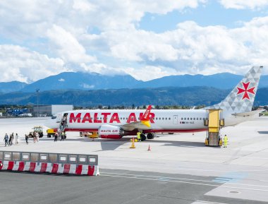 Klagenfurt, Avusturya - 25 Eylül 2025: Malta Hava Yolları, arka planda çarpıcı dağ manzarası bulunan yolcularla birlikte havalimanında konuşlandırıldı