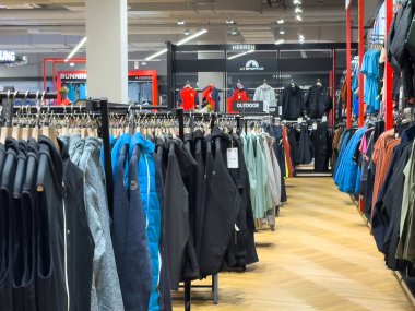 Villach, Avusturya - 17 Eylül 2025: Çeşitli ceket ve giyimlerin sergilendiği bir giyim mağazasının içi, canlı bir alışveriş deneyimi yaratıyor