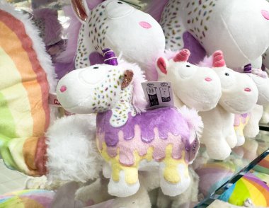 Villach, Avusturya - 17 Eylül 2025: Renkli pelüş tek boynuzlu at oyuncakları çocuklar için canlı desenler ve kaprisli tasarımlar içeren bir rafa dizildi