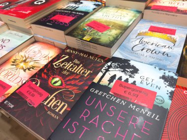 Villach, Avusturya - 17 Eylül 2025: Konforlu bir kitapçıda canlı kapakların ve çeşitli türlerin yer aldığı fiyat etiketli kitaplar dizisi