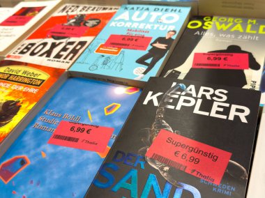 Villach, Avusturya - 17 Eylül 2025: Çeşitli türler ve göz alıcı kapakların yer aldığı bir kitapçıda fiyat etiketli birden fazla kitabın gösterimi