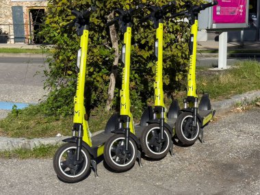 Villach, Avusturya - 17 Eylül 2025: Şehir sakinleri için yenilikçi kentsel hareketlilik çözümlerini temsil eden sarı elektrikli scooterlar kaldırıma park edildi