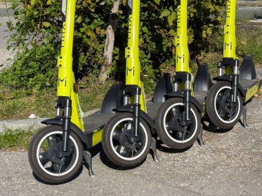 Villach, Avusturya - 17 Eylül 2025: Çevreye duyarlı banliyö sakinleri için yenilikçi kentsel hareketlilik çözümlerini temsil eden sarı elektrikli scooterlar kaldırıma park edildi