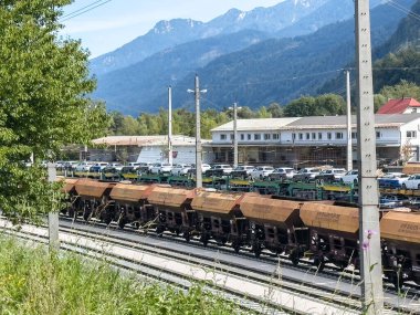 Villach, Avusturya - 17 Eylül 2025: Arkasında dağlar ve yeşillikler olan yük vagonları, ulaşımı ön plana çıkarıyor