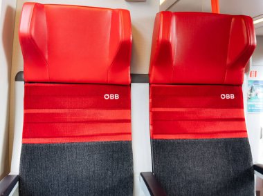 Villach, Avusturya - 17 Eylül 2025: Çağdaş ulaşım ortamında konfor ve tarz için tasarlanmış OBB logosunun yer aldığı kırmızı tren koltukları