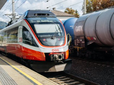 Villach, Avusturya - 17 Eylül 2025 OBB treni sonbahar manzarasında demiryolu ulaşımını ön plana çıkaran yük vagonları ile istasyona geliyor.