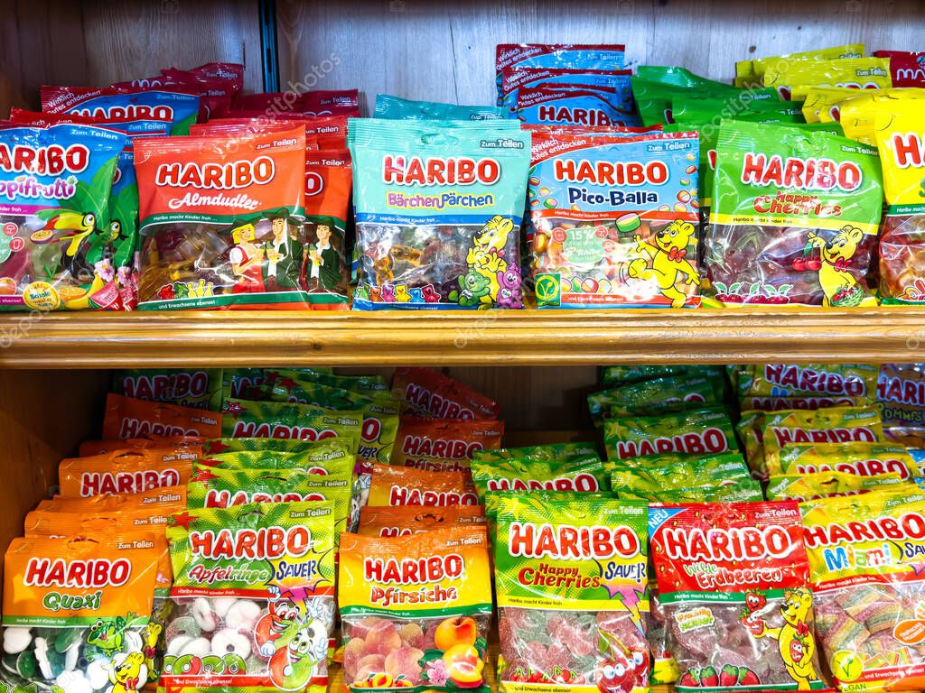 Villach, Austria - September 17, 2025: Vibrant assortment of HARIBO gummy candy packages arranged on wooden shelf, highlighting playful designs and flavors