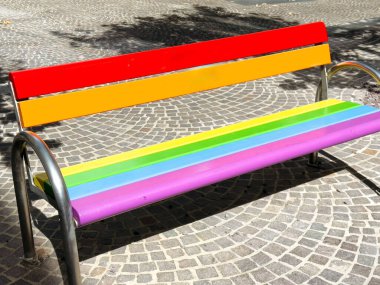 Güneşli şehir parkında kaldırım taşı yolunda renkli gökkuşağı bankı.