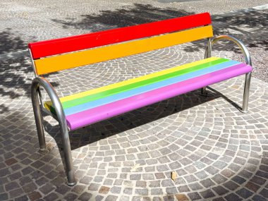 Güneşli park ortamında kaldırım taşı yolunda renkli gökkuşağı bankı.