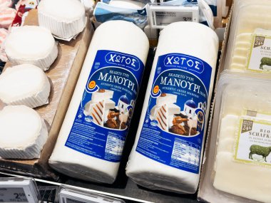 Villach, Austria - September 28, 2025: Greek Manouri cheese in white packaging, showcased in a grocery store among assorted dairy items