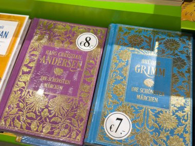 Villach, Austria - September 28, 2025: Colorful books by Andersen and Grimm are displayed on a shelf, highlighting intricate designs and pricing for classic fairy tales