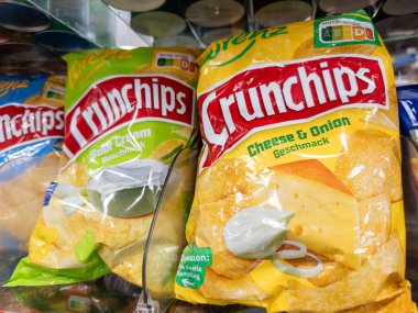 Villach, Austria - September 28, 2025: Crunchips snack bags with cheese and onion and sour cream flavors are prominently displayed in a grocery store aisle