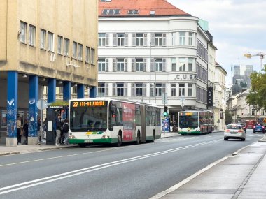 Ljubljana, Slovenia - October 02, 2025: City buses are seen on street with passengers waiting at bus stop, illustrating urban transportation and daily life