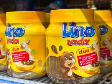 Ljubljana, Slovenia - October 02, 2025: Lino Lada duo hazelnut spread jars are arranged on a supermarket shelf with bright yellow packaging and a cute bear mascot