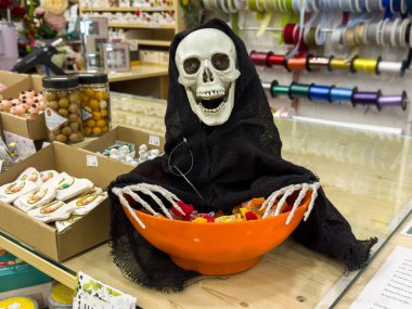 Ljubljana, Slovenia - October 02, 2025: Halloween-themed skeleton decoration with orange bowl of candy, enhancing the festive ambiance in a craft store