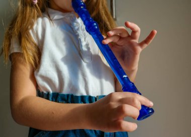 Yeteneğiyle oynayan küçük kız soprano kaydedici, mavi flüt. Kapatın. Yüksek kalite fotoğraf