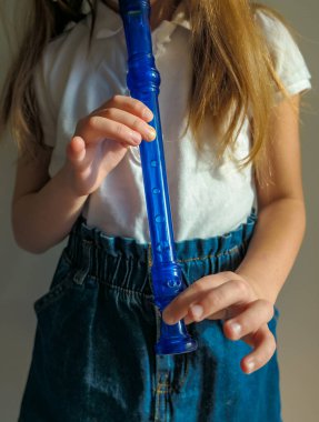 Yeteneğiyle oynayan küçük kız soprano kaydedici, mavi flüt. Kapatın. Yüksek kalite fotoğraf