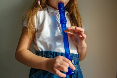 Yeteneğiyle oynayan küçük kız soprano kaydedici, mavi flüt. Kapatın. Yüksek kalite fotoğraf