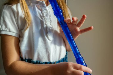 Yeteneğiyle oynayan küçük kız soprano kaydedici, mavi flüt. Kapatın. Yüksek kalite fotoğraf