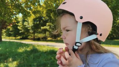 Küçük sevimli bir kız kafasına pembe bir kask takar ve onu takmaya çalışır. Paten kaymayı ya da bisiklete binmeyi öğreniyor. Yüksek kalite 4k görüntü