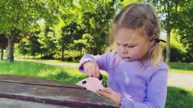 Küçük bir kız, eliyle kafasına pembe bir koruyucu kask takar ve sıkar. Miğfer boyutu, yaz sporları. Yüksek kalite