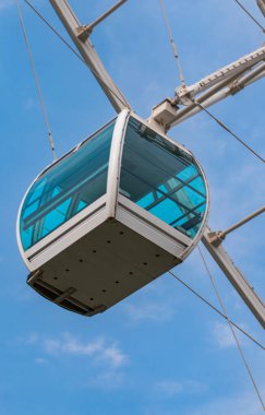 Bulutlu mavi gökyüzünün arka planında modern dönme dolap