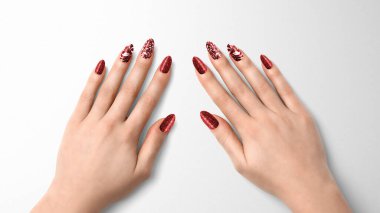 Moda manikür tırnaklı güzel kadın elleri, kırmızı jel cilası, sim ve yaprak tasarımı, artı bir metin alanı.