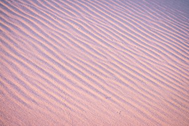 Purple-toned sand dunes with ripples create a captivating natural pattern. The textured surface and calming colors evoke a serene desert landscape, perfect for nature or abstract-focused projects. clipart