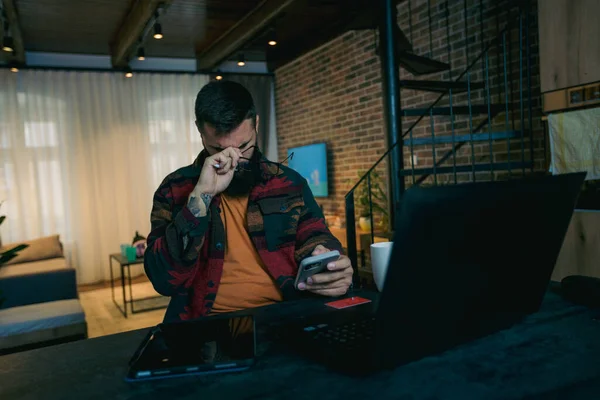 Bütün gün dizüstü bilgisayarı ve tableti üzerinde çalıştıktan sonra yorgun genç adamın başı ağrıyor.