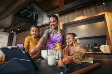 Anne ve kızları hamur işi yapmak için tablette yemek tarifi arıyorlar.