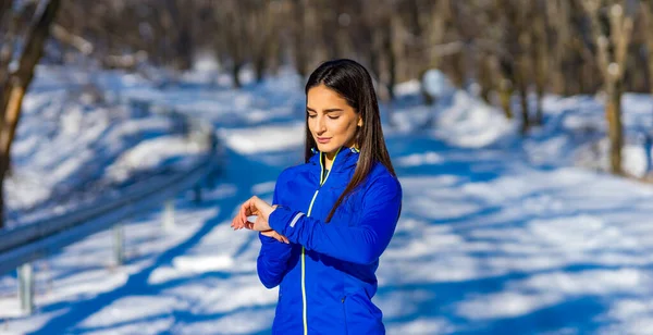 Spor giyim sektöründe güzel bir beyaz kadın akıllı saatini ne zamandır çalıştığına ve ne kadar kalori yaktığına bakar..