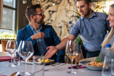 Bir garson, restorana yemeğe gelen genç bir çifte yemek servisi yapıyor..