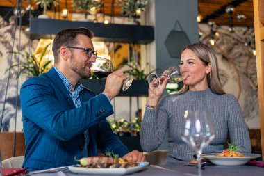 Romantik çift restoranda yemek yiyor, lezzetli yemekler yiyor ve şarap içiyor. Yaşam tarzı, aşk, ilişkiler, gıda konsepti