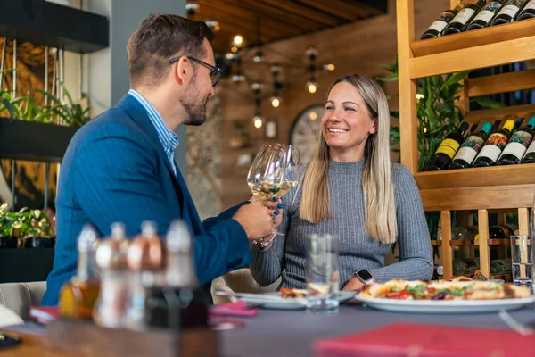 Genç, sevimli bir çift, restoranda kaliteli ve zengin beyaz şarapla daha güzel anlar için kadeh kaldırıyor.
