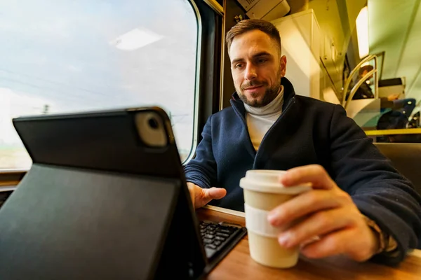 Commuter on his way to work using technology to pass the time, as he drinks coffee