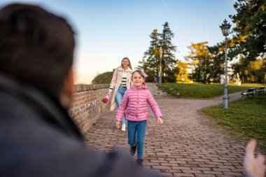Üç kişilik mutlu bir aile yürüyor ve güzel bir kış gününün tadını çıkarıyor..