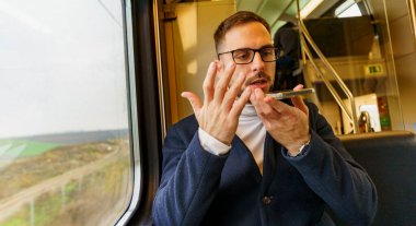 İş adamı trenle gidip geliyor, telefonda iş planları ve fikirlerinden bahsediyor. Ekibinin yaptığı araştırmadan memnun değil.