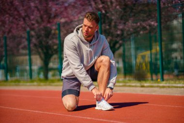 Çapraz Eğitim egzersiz stadyumda bağcık bağlama runner adam. Sportif erkek eğitim dışında