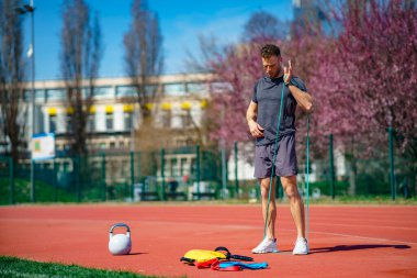 Atletik vücutlu bir adam direnç bandı kullanarak egzersiz yapıyor..