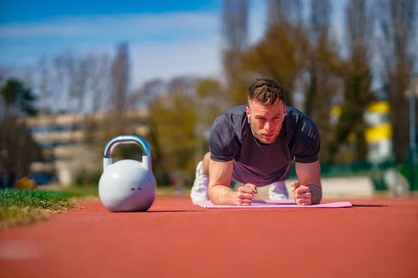 Seorang Olahragawan Dengan Earphone Melakukan Latihan Papan Atas Tikar Kebugaran — Stok Foto