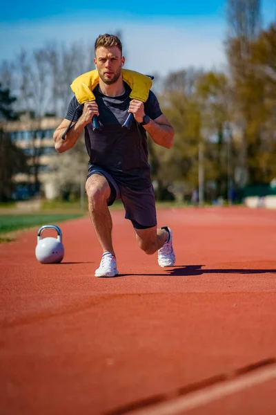 肌肉发达的年轻人带着沉重的袋子在体育馆里锻炼 体形魁梧的人拿着沉重的袋子锻炼 — 图库照片